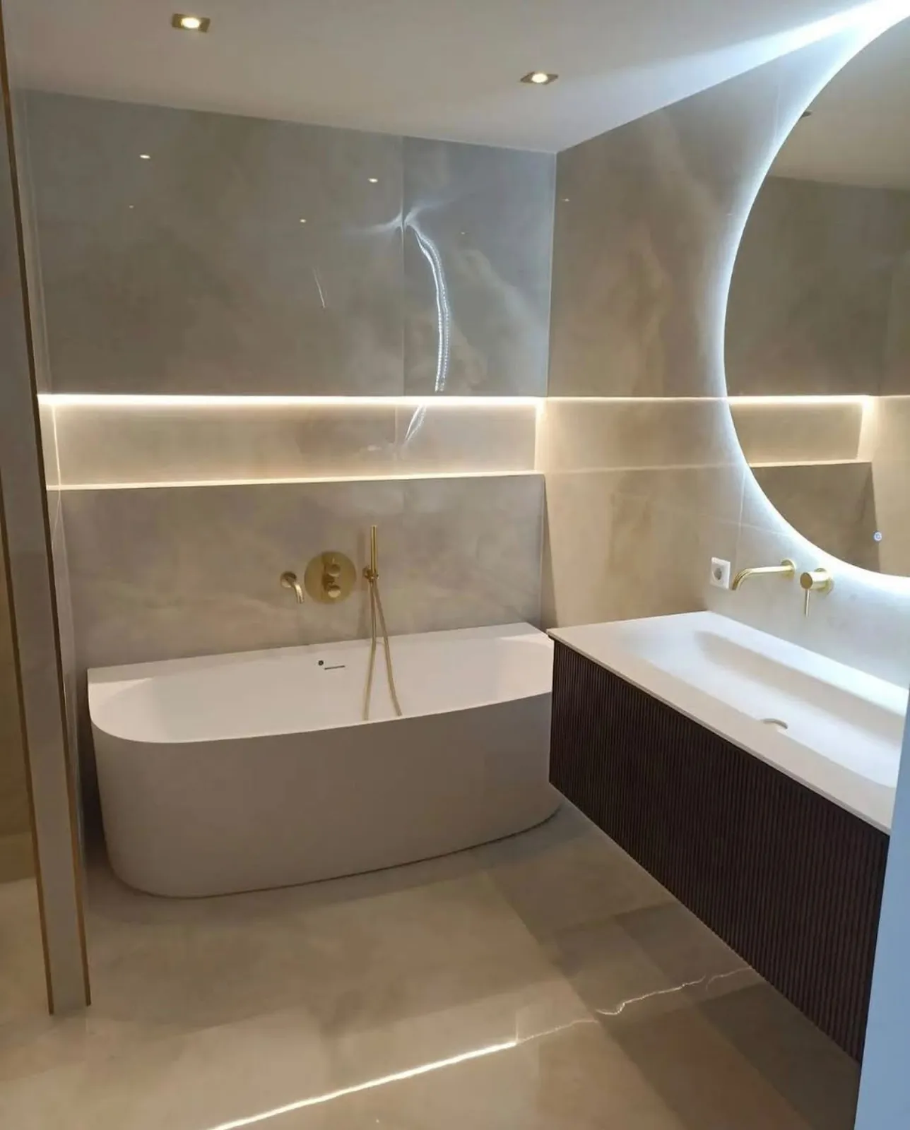 Gerenoveerde badkamer met vrijstaand ligbad, marmerlook tegels en gouden kranen