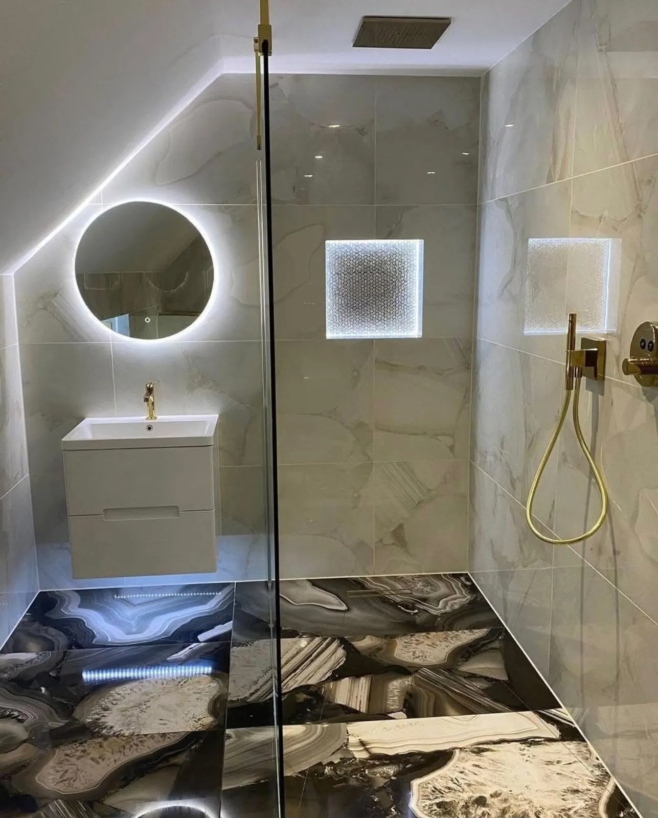 Badkamer met ronde verlichte spiegel, wit meubel en gouden handdouche