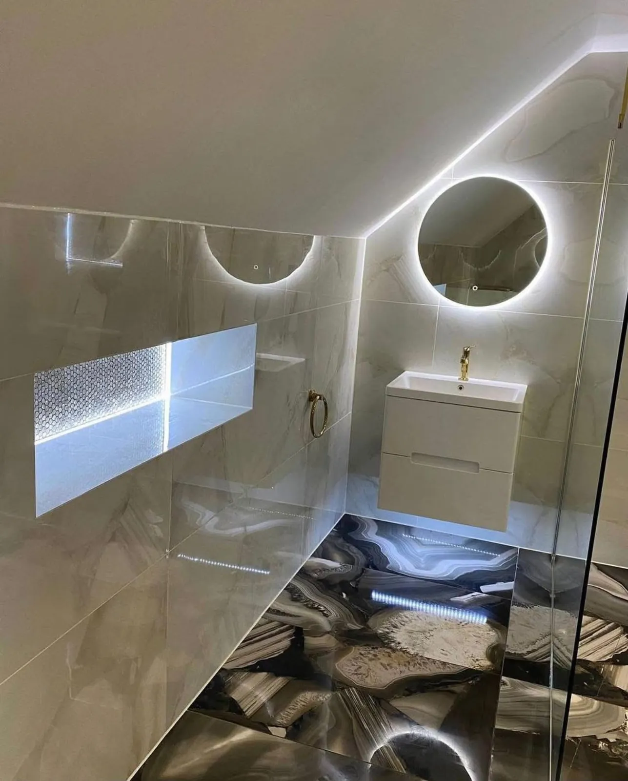 Badkamer onder schuin dak met verlichte nis en ronde spiegel