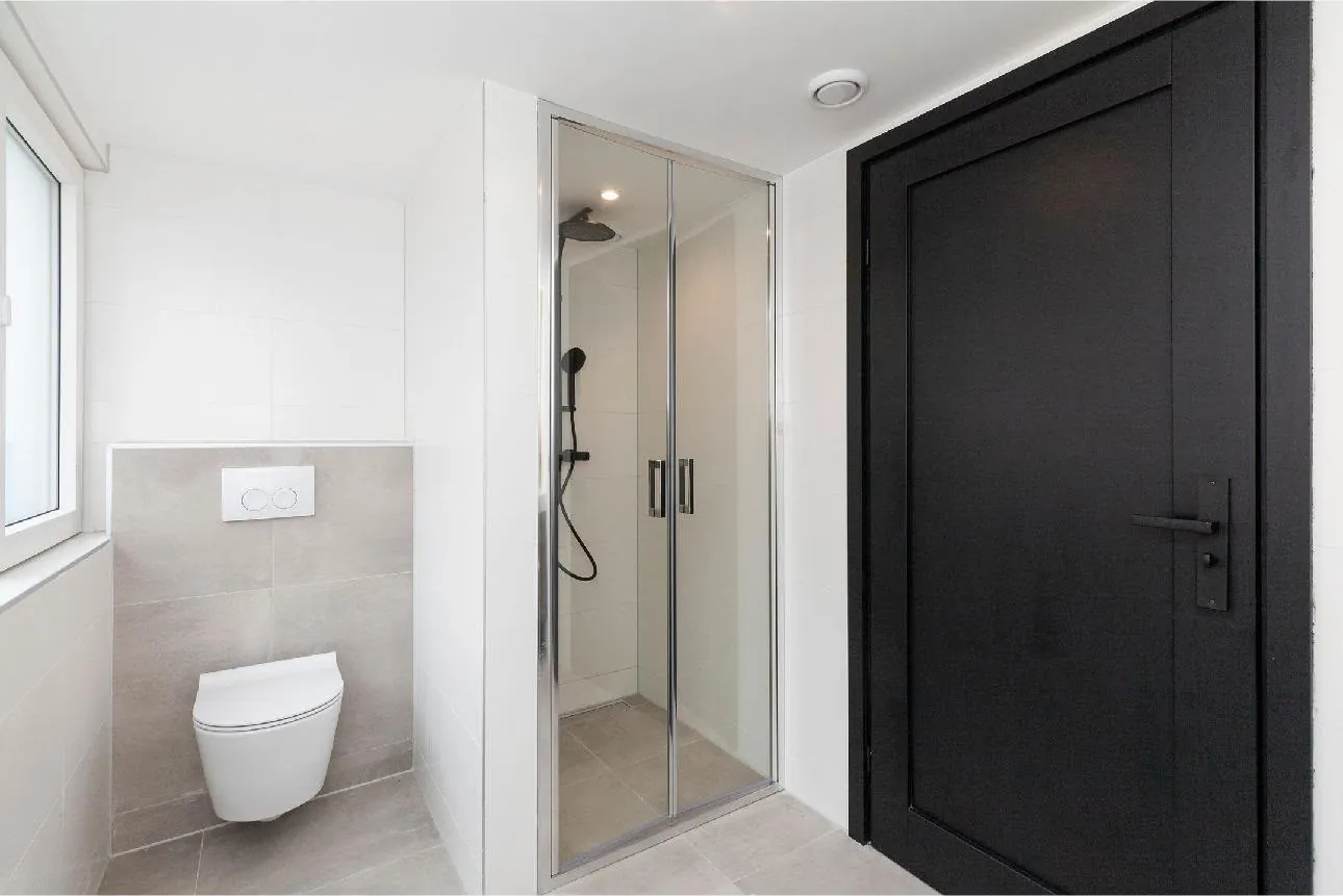 Gerenoveerde badkamer met zwarte deur en hangtoilet