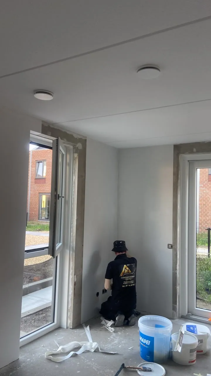 Schilder werkt een wand en kozijn af bij openslaande deuren