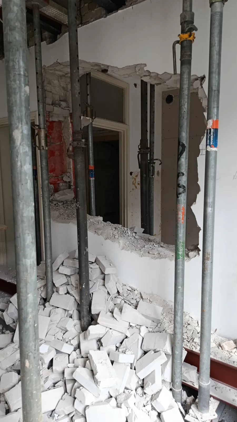 Gedeeltelijk gesloopte wand met stempels en puin