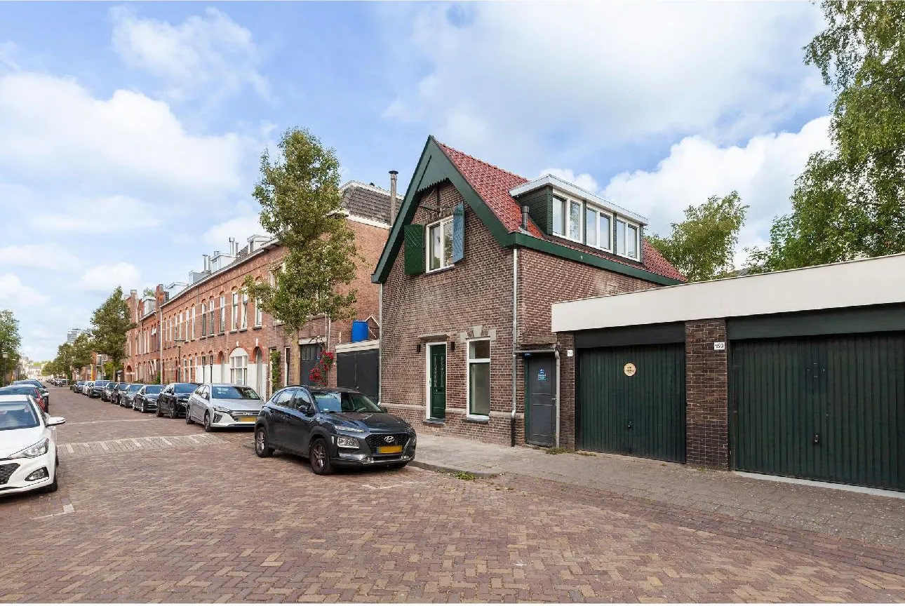 Straat met woningen en een vrijstaand huis met groene dakkapel