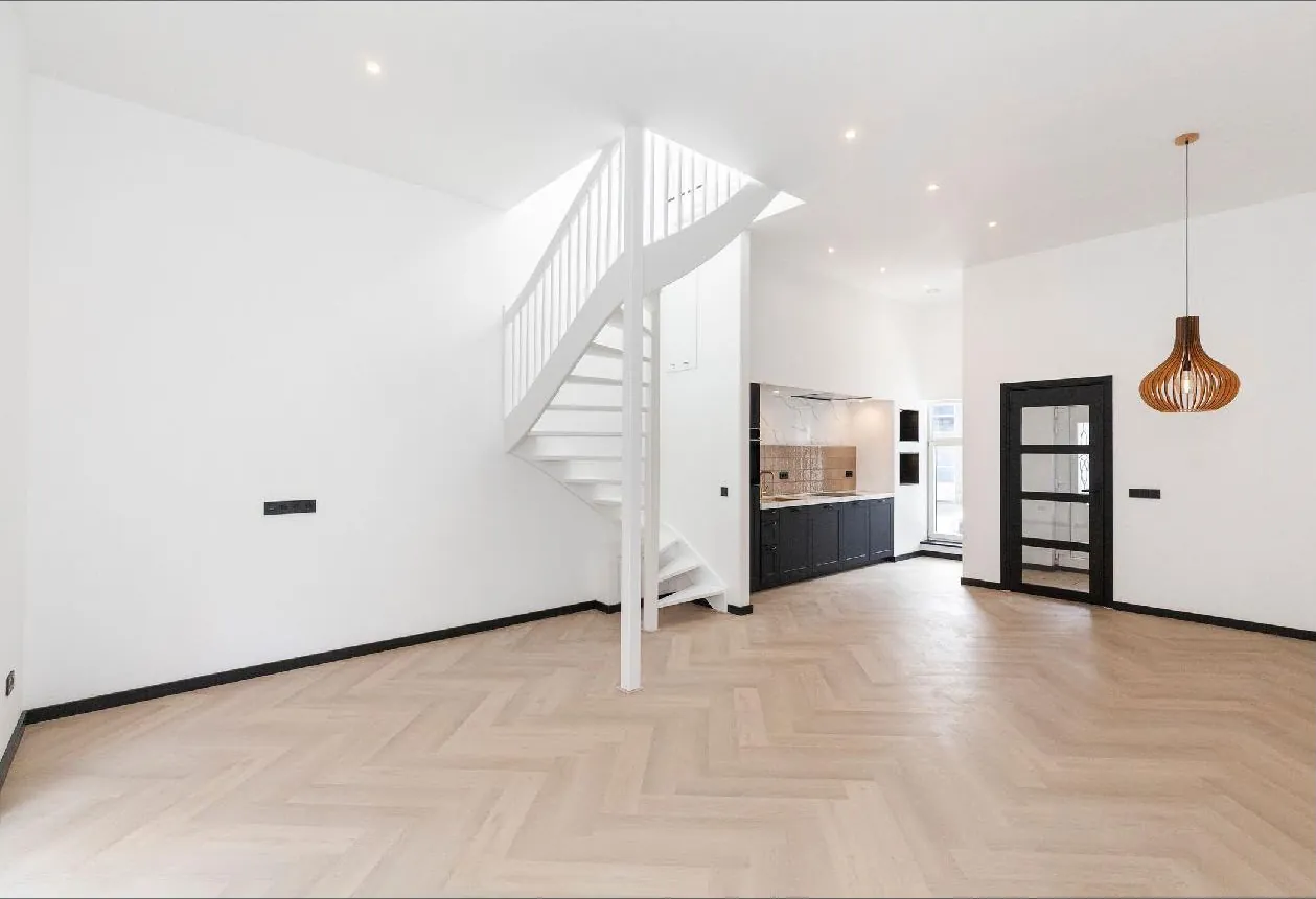 Gerenoveerde woonkamer met witte trap, visgraatvloer en open keuken