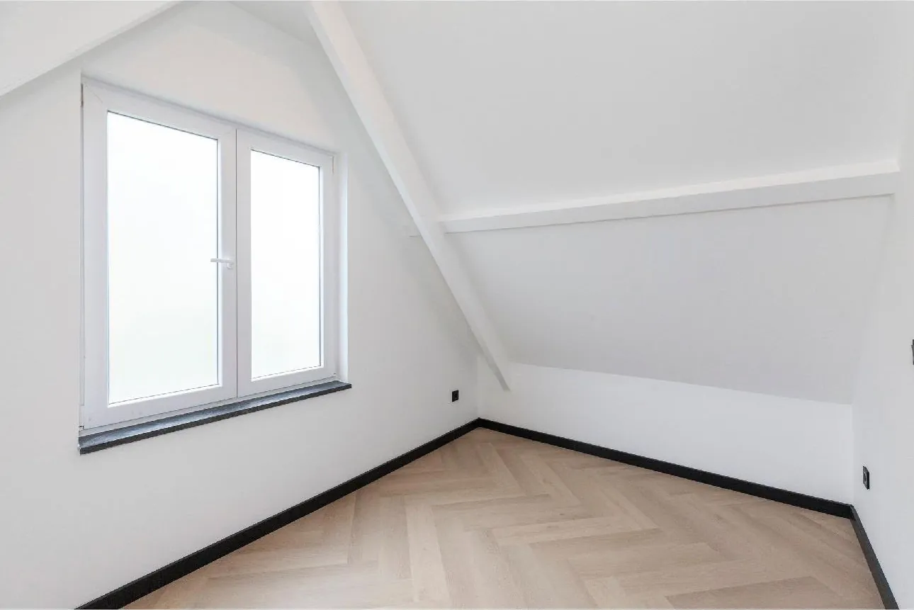 Zolderkamer met lichte visgraatvloer en witte plinten